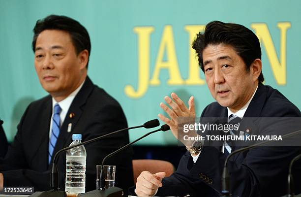 Japanese Prime Minister and ruling Liberal Democratic Party leader Shinzo Abe answers a question beside Democratic Party of Japan leader Banri Kaieda...