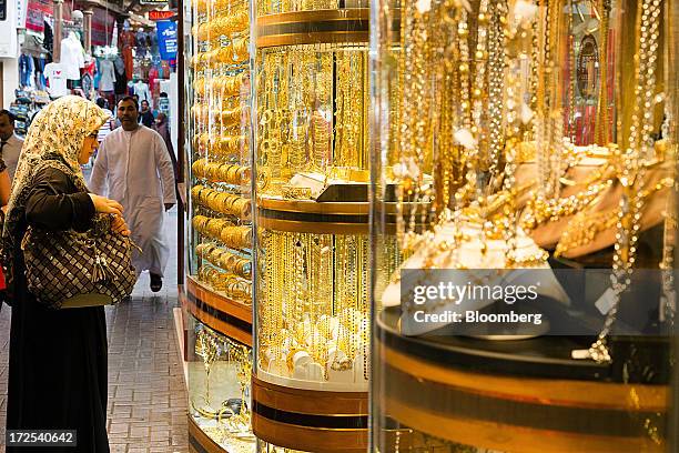 Shopper browses gold jewelry on display in the windows of a gold store in the Dubai Gold Souk in the Deira district of Dubai, United Arab Emirates,...