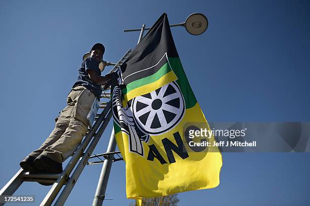 Activists hang flags on lamp post near the Vilakazi Street home of Nelson Mandela who is being treated for a recurring lung infection in hospital on...