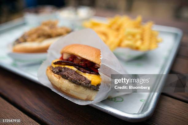 Shake Shack cheeseburger sits with a portion of fries on a tray outside the company's new burger restaurant in London, U.K., on Tuesday, July 2,...