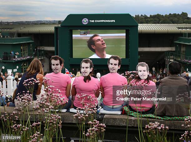 Tennis fans wearing masks depicting Britain's Andy Murray watch a giant TV screen showing his match against Fernando Verdasco of Spain in their...