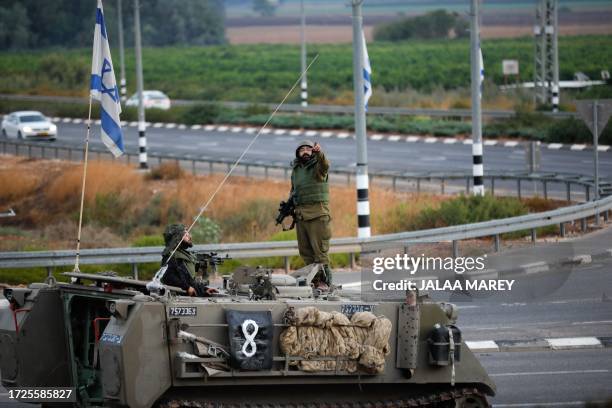 An Israeli army armoured vehicle drives to a position at a junction near the northern Qiryat Shemona city near the border with Lebanon on October 15,...