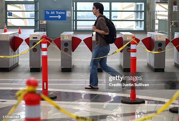 Commuter walks by closed pay gates at the Bay Area Rapid Transit Millbrae station on July 3, 2013 in Millbrae, California. For a third day, hundreds...