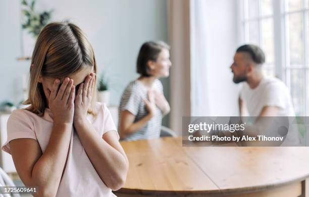 little girl, daughter suffers from her parents fighting, quarrelling, screaming, sorting their relations at home. - divorce photos et images de collection