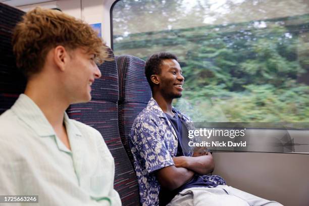 two young men chatting on a train together - travel and not business stock pictures, royalty-free photos & images