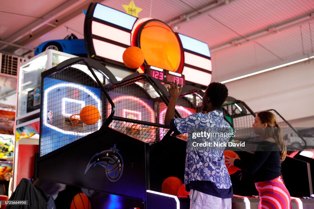 Two young adults having fun shooting basketball hoops at an amusement arcade - seaside UK