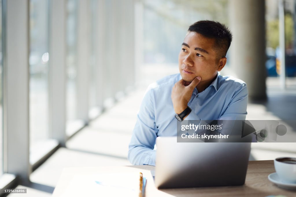 Pensive Asian businessman working on laptop in the office.
