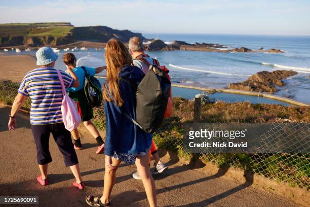 a group of senior swimmers walking along a coastal path to the sea - confidence male landscape stock pictures, royalty-free photos & images