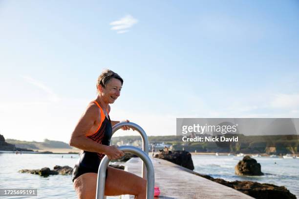 a senior women enjoying a swim at a tidal swimming pool - disrupt aging stock pictures, royalty-free photos & images