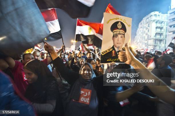 People celebrate at Tahrir Square with a portrait of Army chief Abdel Fattah al-Sisi after a broadcast confirming that the army will temporarily be...