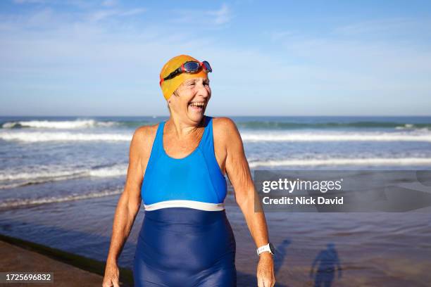 a portrait of a cheerful female senior swimmer smiling off camera - swimming cap stock pictures, royalty-free photos & images