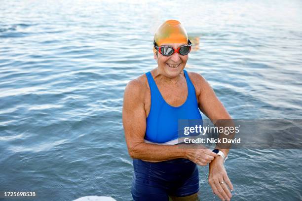 a senior women adjusting her fitness activity tracker before swimming - wearable computer stock pictures, royalty-free photos & images