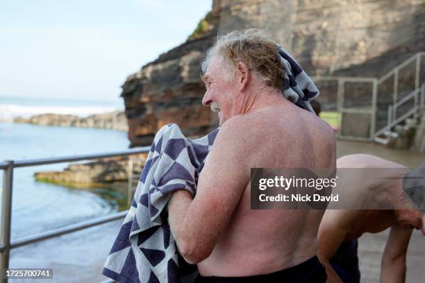 a senior male swimmer getting changed after a swim at a tidal sea pool - afterr stock pictures, royalty-free photos & images