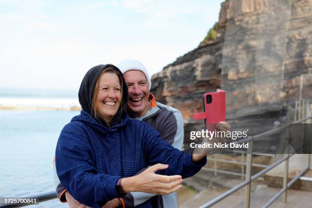 a mature couple taking a selfie after swimming in the sea - older man real life stock pictures, royalty-free photos & images