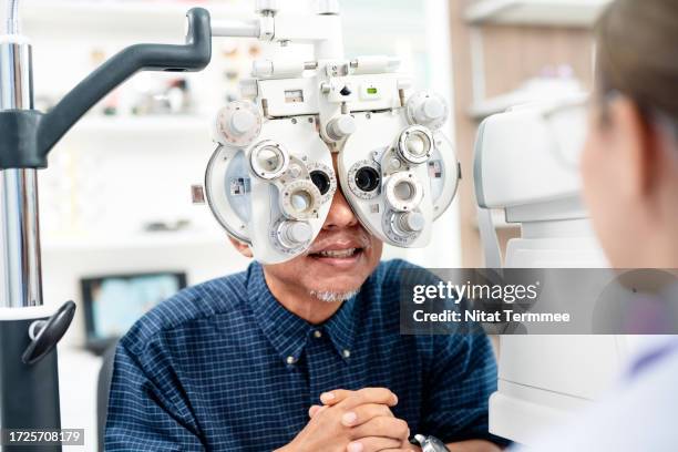 eye exams may help identify seniors at risk of eye health. a senior patient getting an eye exam by an automated phoropter with an ophthalmologist advising in an ophthalmology clinic. - augenuntersuchung stock-fotos und bilder