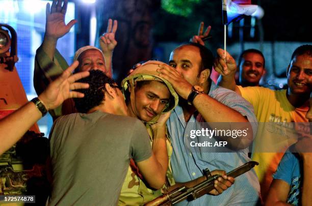 Egyptians hug and kiss an army soldier after a broadcast confirming the army will temporarily be taking over from the country's first democratically...