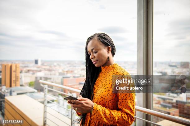 black business woman looking at mobile on roof terrace in berlin - berlin diversity alexanderplatz stockfoto's en -beelden