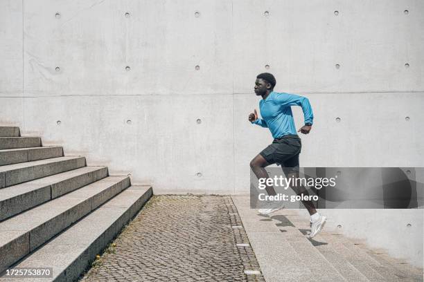 junger sportler läuft stufen im freien in berlin hinauf - läufer athlet stock-fotos und bilder