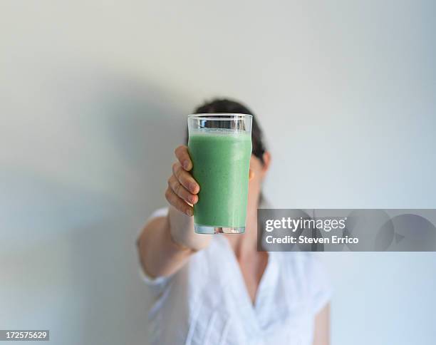 woman holding up glass of fresh vegetable juice - femme visage caché photos et images de collection