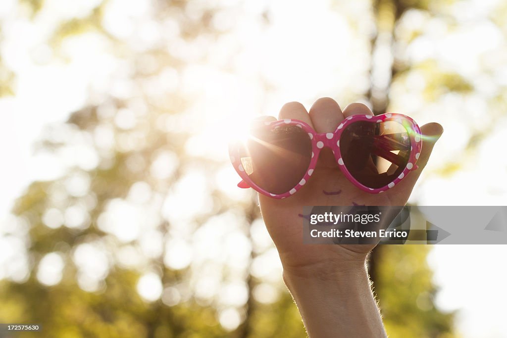 Happy face and sunglasses on a hand