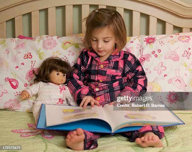 small girl reading to her doll in bed - american girl doll 個照片及圖片檔