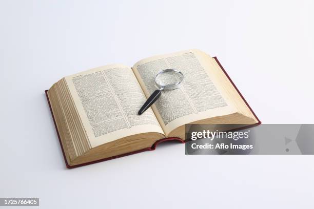 dictionary and magnifying glass - definition stock-fotos und bilder