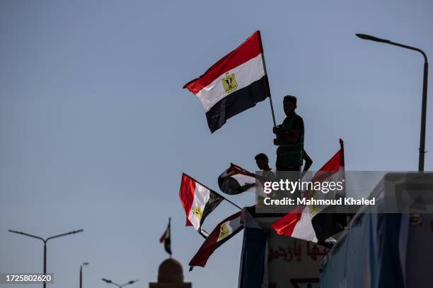 Volunteers carry Egyptian flags as they wait with aid convoy trucks loaded with supplies near the North Sinai Governorate building on October 15,...