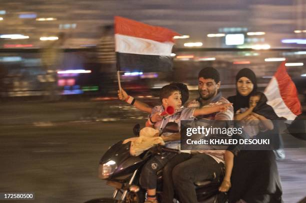 An Egyptian family on motorcycle celebrates in Cairo on July 3, 2013 after a broadcast confirming that the army will temporarily be taking over from...