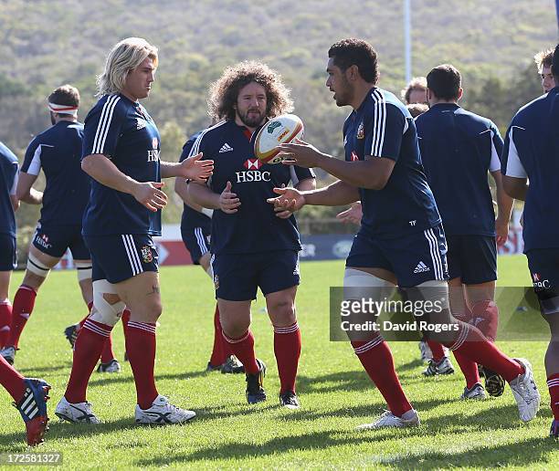 Toby Faletau passes the ball to Richard Hibbard as Adam Jones looks on during a British & Irish Lions training session at Noosa Dolphins RFA on July...