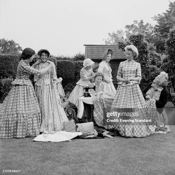 Group of teenage girls and women dressed in Victorian dresses, stand in a garden during the Broadstairs Dickens Festival, Kent, June 18th 1958.