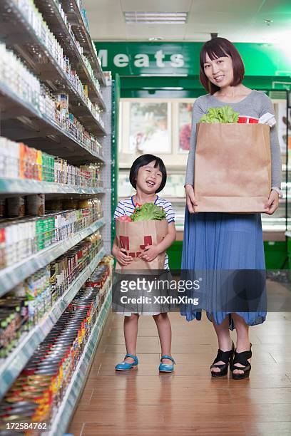 mother and daughter holding grocery bags in supermarket, beijing - young choice beijing activity stock pictures, royalty-free photos & images