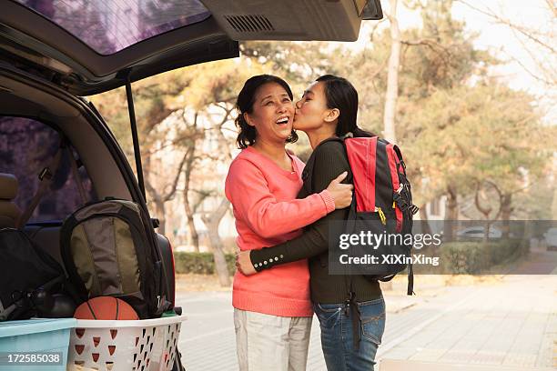 mother and daughter embracing behind car on college campus - womens college basketball stock-fotos und bilder