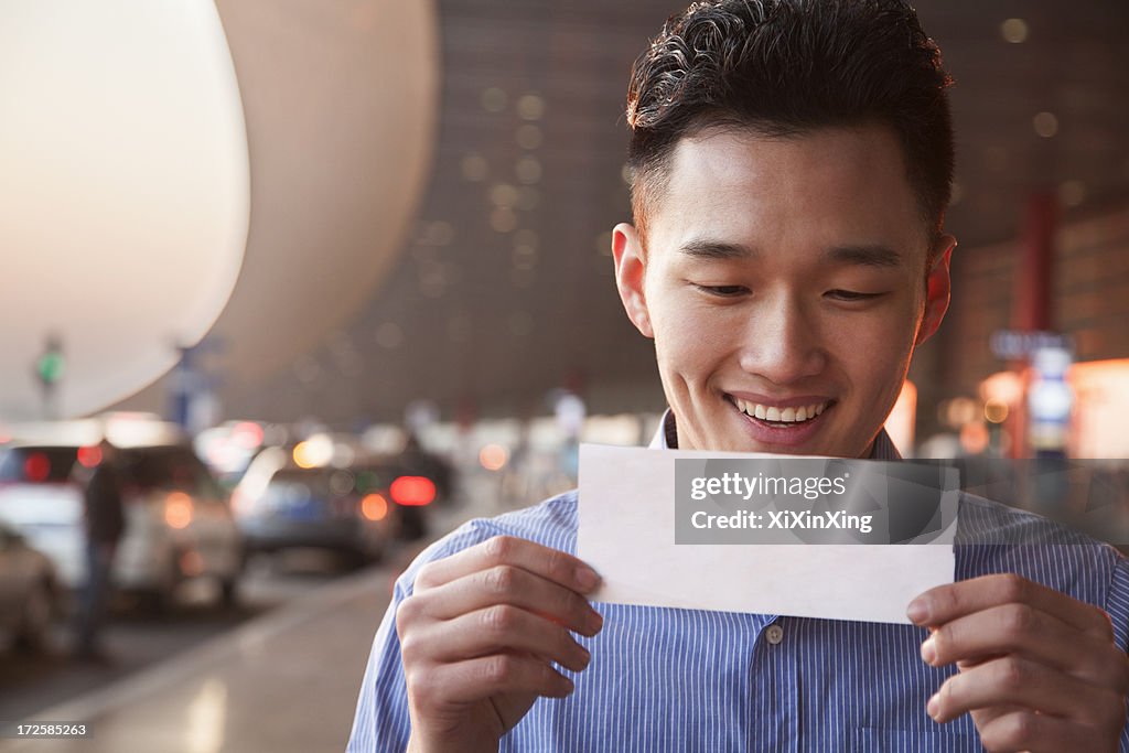 Young traveler looking at ticket at airport