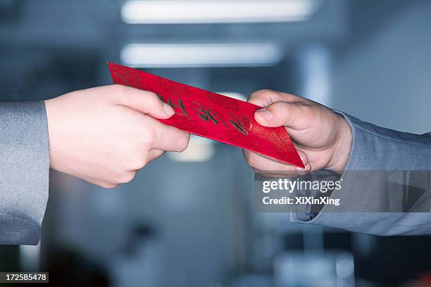 close up on hands exchanging a red chinese new years envelope - chinese new year red envelope stock pictures, royalty-free photos & images