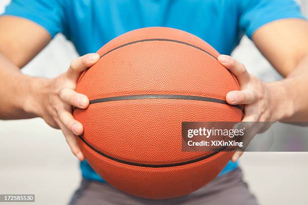 close up of young man, midsection, holding a basketball - basketball close up stock-fotos und bilder