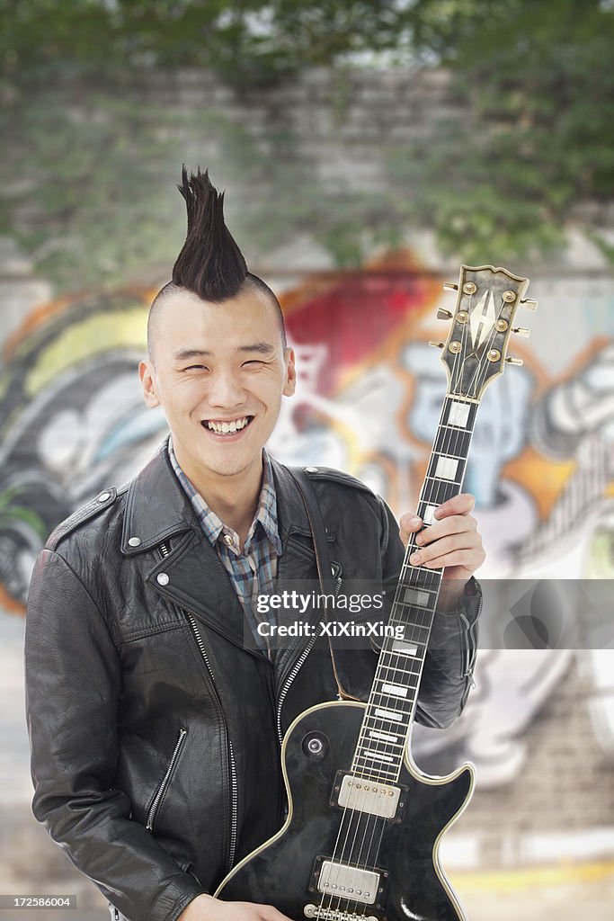 Young man with punk Mohawk holding guitar