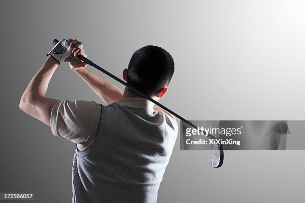 young golf player swinging, rear view - golf short iron stock pictures, royalty-free photos & images