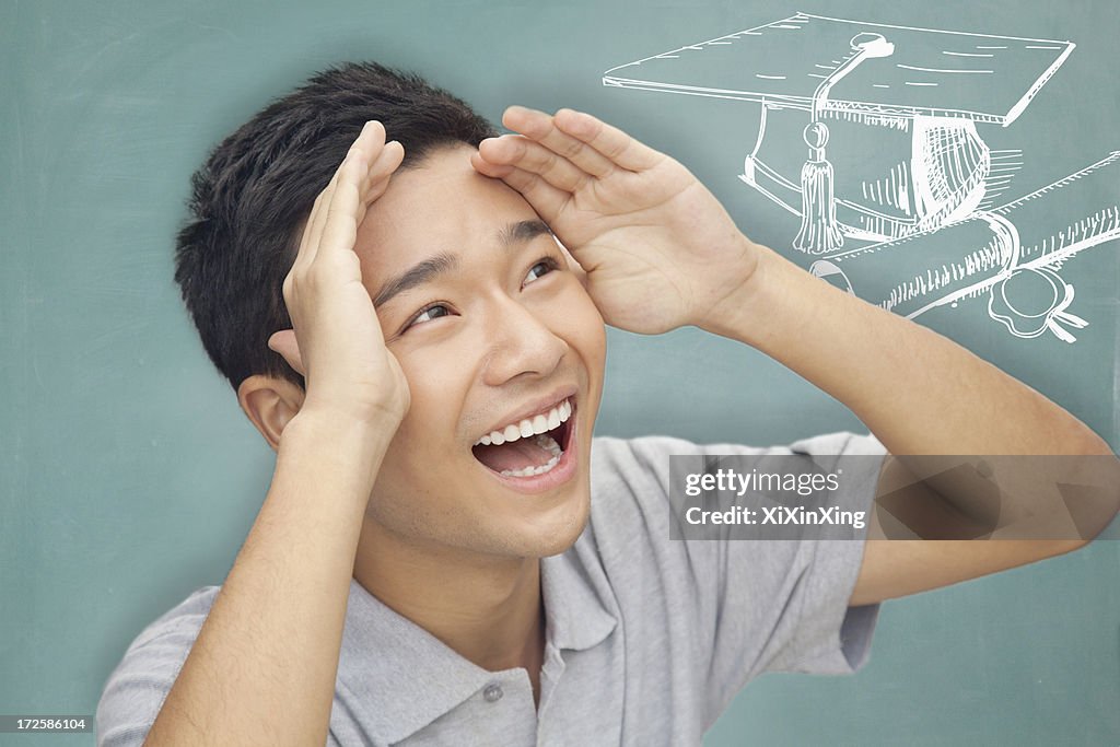 Portrait of young man with arms raised up and looking to the future, graduation and education