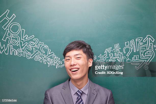 portrait of young businessman in front of black board with chinese and english script - niet westers schrift stockfoto's en -beelden