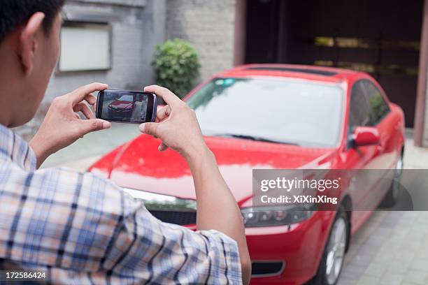 young man taking a picture of his car - autofoto stockfoto's en -beelden