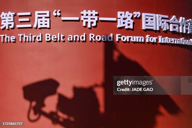 The shadow cast by a surveillance camera is seen on an installation of the Belt and Road Forum along a street in Beijing on October 15, 2023.