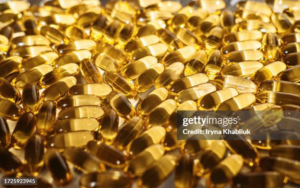 soft yellow vitamin d, omega-3, fish oil capsules on sunlight white background. fish oil capsules with omega 3 and vitamin d. soft capsule heap back-lit background - vitamine d stockfoto's en -beelden