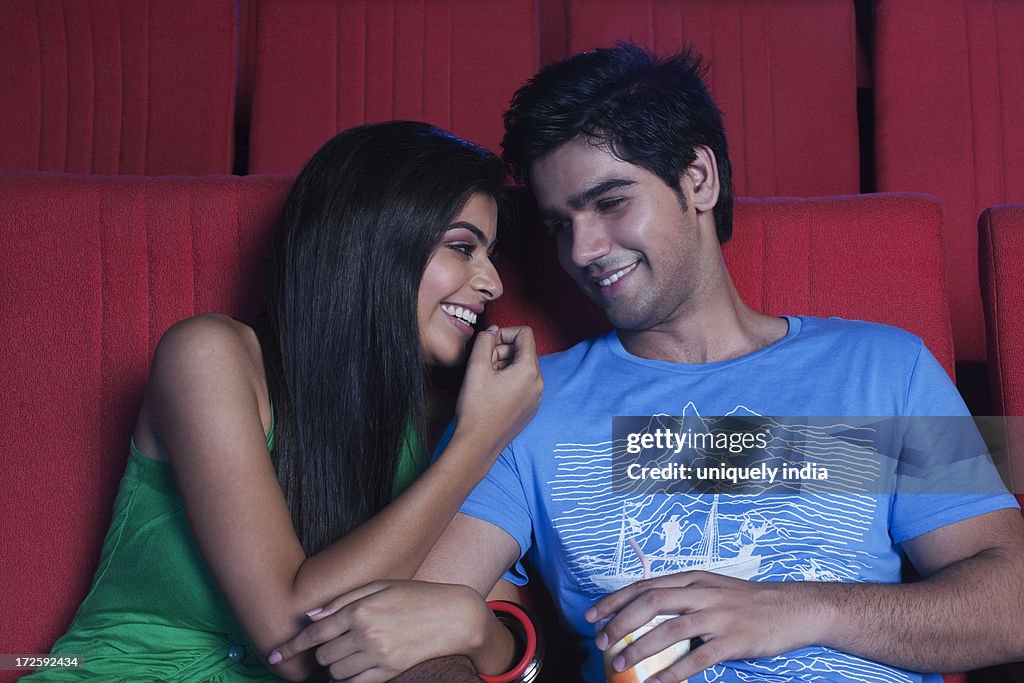 Couple smiling at each other in a cinema hall