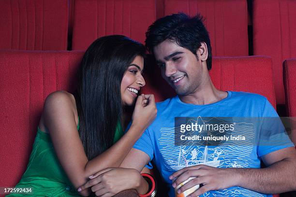 couple smiling at each other in a cinema hall - indian couple in theaters stock pictures, royalty-free photos & images