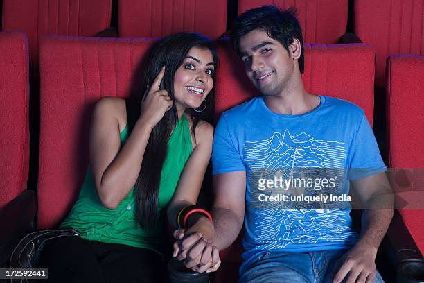 couple enjoying movie in a cinema hall - indian couple in theaters stock pictures, royalty-free photos & images