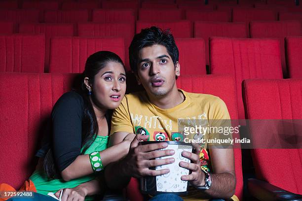 couple watching a horror movie in a cinema hall - indian couple in theaters stock pictures, royalty-free photos & images