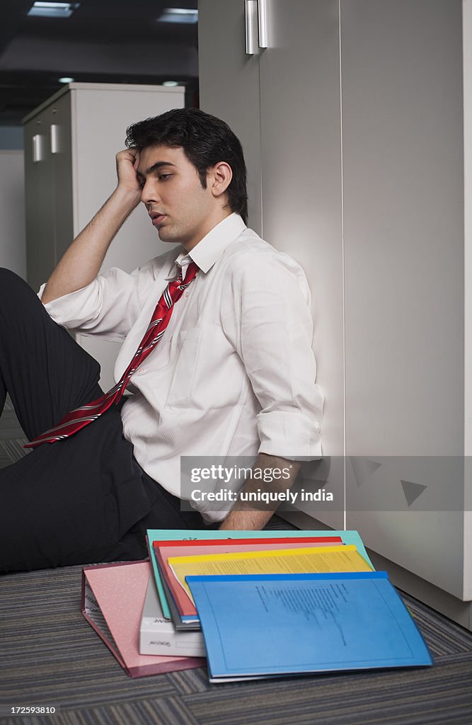 Businessman leaning against a cabinet in the corridor