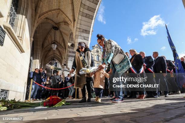 People lay a bunch of flowers as they gather with local officials to pay tribute at Heroes square in Arras, northeastern France on October 15 two...