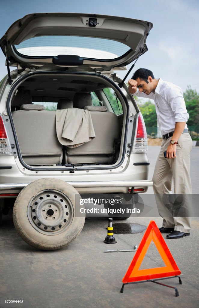 Worried businessman standing behind a breakdown car