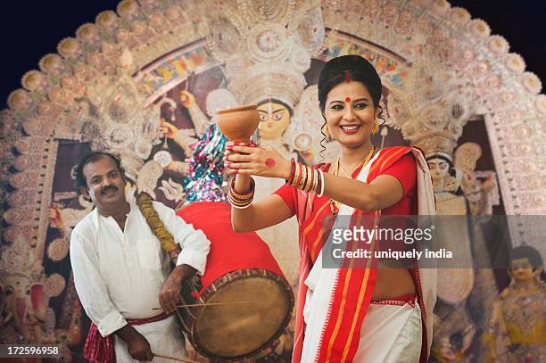 bengali woman performing dhunachi dance and a dhaki playing dhak at durga puja - durga puja stock pictures, royalty-free photos & images